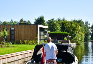 Hombre en un barco en Villa Nautica, MarinaPark Residentie Nieuw Loosdrecht, Países Bajos, con bandera.