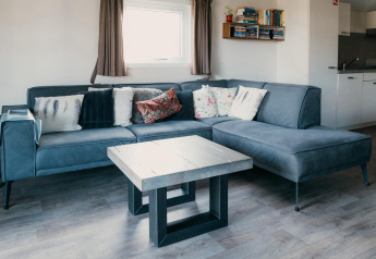 Soggiorno moderno con divano angolare blu e cuscini presso Veluwe lounge + sauna, De Boshoek, Paesi Bassi.