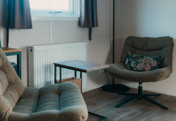 Zona de salón acogedora con sillones, mesa y cojín floral en Veluwe lounge + sauna de De Boshoek, Países Bajos.