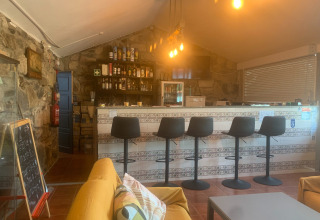 Indendørs barområde på Glamping de Cerveira, Portugal, med moderne stole og hyggelig belysning.