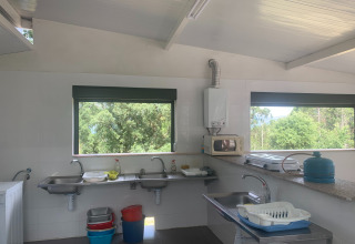 Et lyst fælleskøkken med store vinduer på Glamping de Cerveira feriepark i det nordlige Portugal.