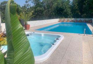 Udendørs pool og spabad omgivet af planter og potter på Glamping de Cerveira feriepark i Nordportugal.