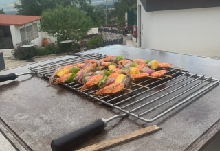 Grillspyd med rejer og grøntsager på en udendørs grill ved Glamping de Cerveira, Portugal, med naturskøn udsigt.