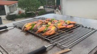 Brochetas de camarones y verduras en una parrilla en Glamping de Cerveira, Portugal, con hermosa vista exterior.