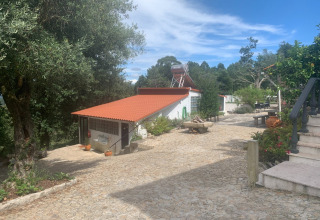 Stenbelagt sti og bygninger i Glamping de Cerveira, feriepark i det nordlige Portugal, omgivet af natur.