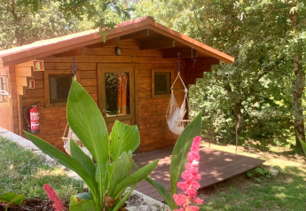 Træhytte kaldet Azalea Cabin ved Glamping de Cerveira i Portugal, omgivet af frodig natur og blomster.