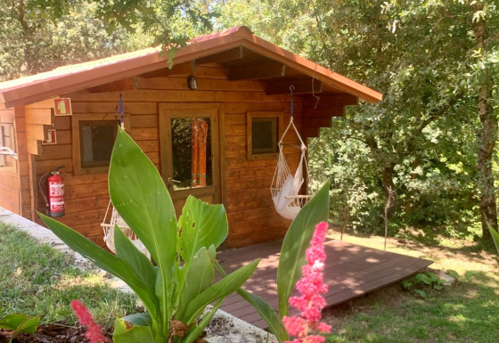 Træhytte kaldet Azalea Cabin ved Glamping de Cerveira i Portugal, omgivet af frodig natur og blomster.