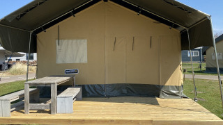 Safari-telt med trædæk og bænk på Holiday Park Duinhoeve i Holland under en klar blå himmel.