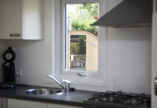 Vista de cocina al sauna desde la ventana en Veluwe lodge en Holiday park De Boshoek, Países Bajos.