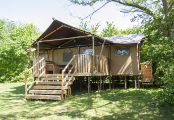 Glampinglodge GL au Holiday Park BreeBronne aux Pays-Bas, entouré de verdure et d’arbres luxuriants.