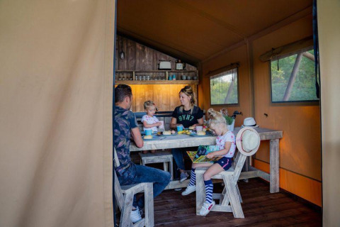 Una familia comparte una comida dentro de la Glampinglodge GL en Holiday Park BreeBronne en los Países Bajos.