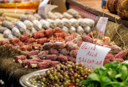 Escena de mercado cerca de Candemil, norte de Portugal, con diversos embutidos, aceitunas y hierbas frescas.