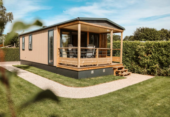 Tiny Lodge, una mini casa al parco vacanze De Boshoek nei Paesi Bassi con veranda e prato verde.