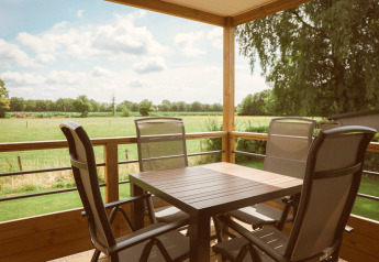 Terrazza con quattro sedie e tavolo alla Tiny Lodge, Holiday park De Boshoek, nei Paesi Bassi.