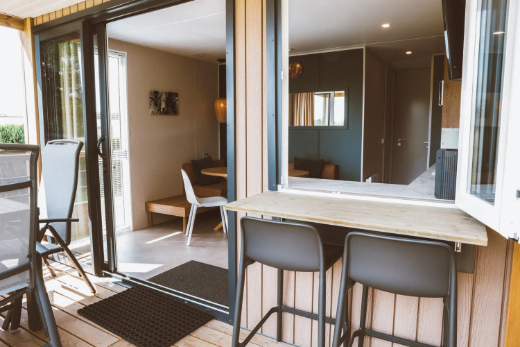 Outdoor and indoor seating area in a Tiny Lodge at Holiday park De Boshoek, Netherlands, with modern decor.
