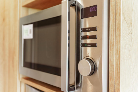 Forno a microonde moderno nella cucina compatta della Tiny Lodge all’Holiday park De Boshoek, Paesi Bassi.