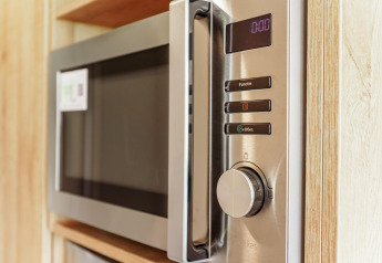 Ingebouwde microgolfoven in de compacte keuken van een Tiny Lodge bij Holiday park De Boshoek, Nederland.