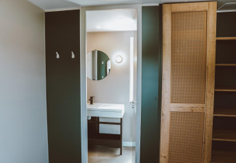 Bagno moderno e zona armadi con specchio e mobili in legno in una sistemazione di glamping di lusso.