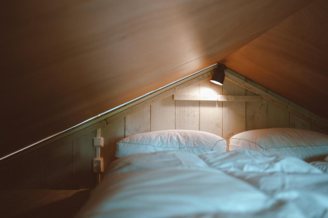 Gemütlicher Schlafbereich mit Deckenbeleuchtung im Tiny Safari House im Ferienpark De Boshoek, Niederlande.