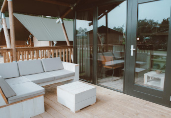 Terrasse extérieure avec canapé et table au Tiny Safari House, Holiday park De Boshoek, Pays-Bas.