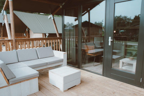 Terrasse extérieure avec canapé et table au Tiny Safari House, Holiday park De Boshoek, Pays-Bas.