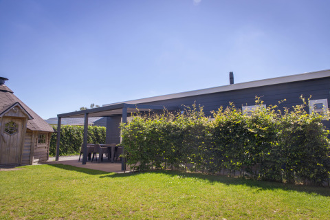 Buitenfoto van Veluwelodge XL bij Vakantiepark De Boshoek in Nederland, met zonnig weer en groene tuin.