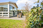 Buitenaanzicht van Veluwe Lounge lodge bij Holiday park De Boshoek in Nederland met glazen wanden en terras.