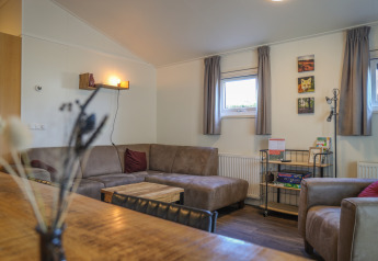Living room inside Veluwe Lounge at De Boshoek holiday park, Netherlands, featuring sofa and board games.