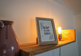 Cozy shelf in Veluwe Lounge at Holiday park De Boshoek, Netherlands, with frame and warm lighting.
