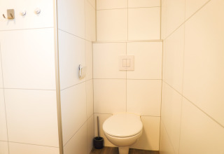 Moderne, minimalistisk badeværelse på Veluwe Lounge i Holiday park De Boshoek med væghængt toilet.