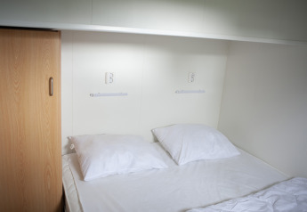 Area notte con letto matrimoniale, cuscini bianchi, armadio e prese alla Veluwe Lounge, De Boshoek, Paesi Bassi.