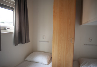 Dos camas individuales separadas por un armario en Veluwe Lounge, Holiday park De Boshoek, Países Bajos.