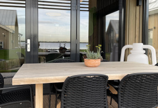 Zona de comedor exterior en la Villa Oesterdam Royal del Oesterdam Resort en los Países Bajos con vistas al agua.