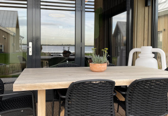 Zona de comedor exterior en la Villa Oesterdam Royal del Oesterdam Resort en los Países Bajos con vistas al agua.