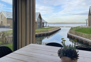 Uitzicht vanuit Villa Oesterdam Royal bij Oesterdam Resort in Nederland met water, huisjes en plant op tafel.