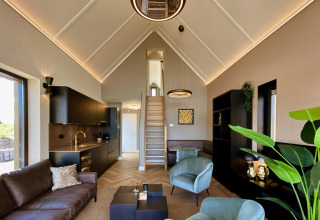 Sala moderna en una tiny house Villa Oesterdam Royal del Oesterdam Resort, con loft y cocina integrada.