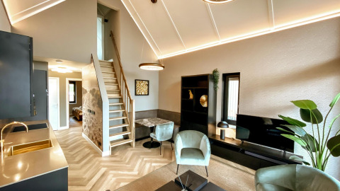 Sala moderna con techos altos, cocina y escaleras en una tiny house de Villa Oesterdam Royal, Países Bajos.