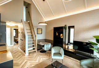 Sala moderna con techos altos, cocina y escaleras en una tiny house de Villa Oesterdam Royal, Países Bajos.