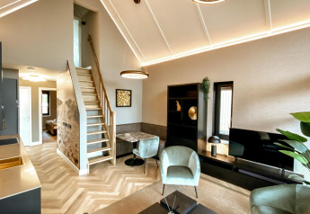 Sala moderna con techos altos, cocina y escaleras en una tiny house de Villa Oesterdam Royal, Países Bajos.
