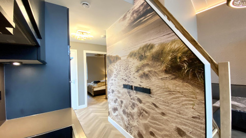 Interior de casa pequeña moderna en Villa Oesterdam Royal, Oesterdam Resort, Países Bajos, con mural de playa.