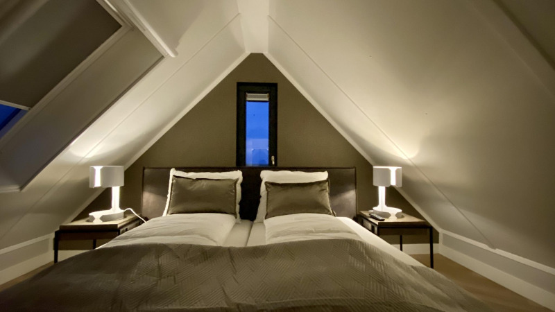 Slaapkamer in Villa Oesterdam Royal, Oesterdam Resort, Nederland, met tweepersoonsbed en schuin plafond.