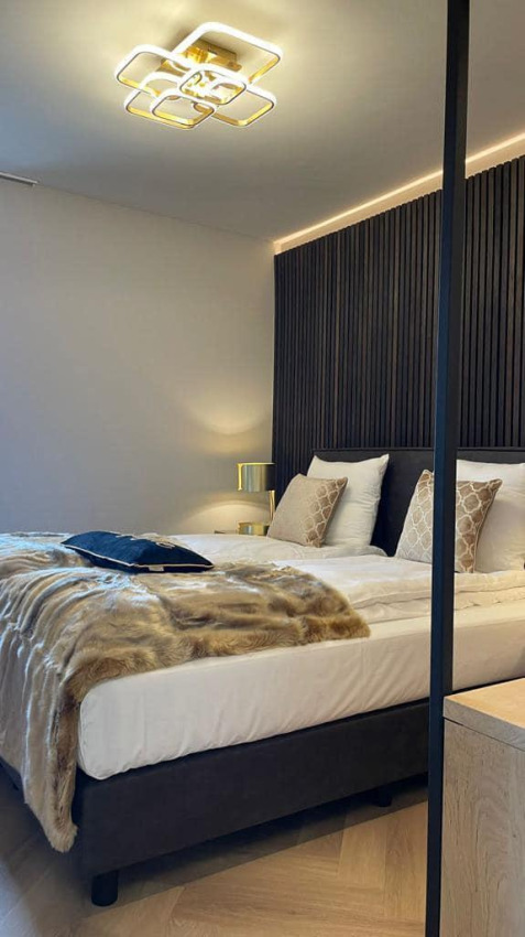 Modern slaapkamerinterieur in Villa Oesterdam Royal, Oesterdam Resort, met smaakvol bed en sfeerverlichting.