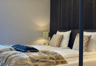 Modern slaapkamerinterieur in Villa Oesterdam Royal, Oesterdam Resort, met smaakvol bed en sfeerverlichting.