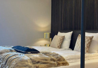 Moderne slaapkamer in Villa Oesterdam Royal, Oesterdam Resort, Nederland, met stijlvol bed en verlichting.