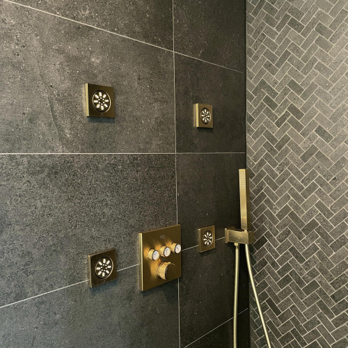 Moderne Dusche mit mehreren goldenen Duschköpfen und dunklen Fliesen in einer Villa Oesterdam Royal.