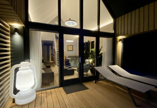 Buitenterras met ligstoelen en lantaarn bij Villa Oesterdam Royal, tiny house in Oesterdam Resort, Nederland.