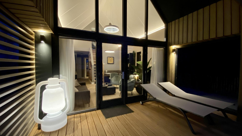 Buitenterras met ligstoelen en lantaarn bij Villa Oesterdam Royal, tiny house in Oesterdam Resort, Nederland.