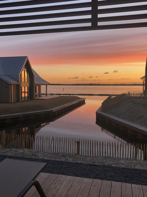 Prachtig zicht op de zonsondergang aan het water bij Villa Oesterdam Royal, Oesterdam Resort met moderne huisjes.