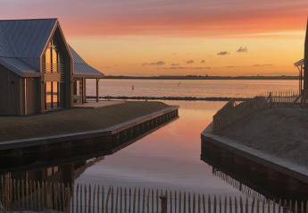 Prachtig uitzicht op zonsondergang boven het water bij Villa Oesterdam Royal, Oesterdam Resort met moderne huisjes.