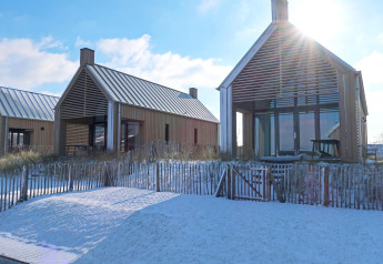 Deux tiny houses modernes avec de grandes fenêtres et de la neige devant à Oesterdam Resort, Pays-Bas.